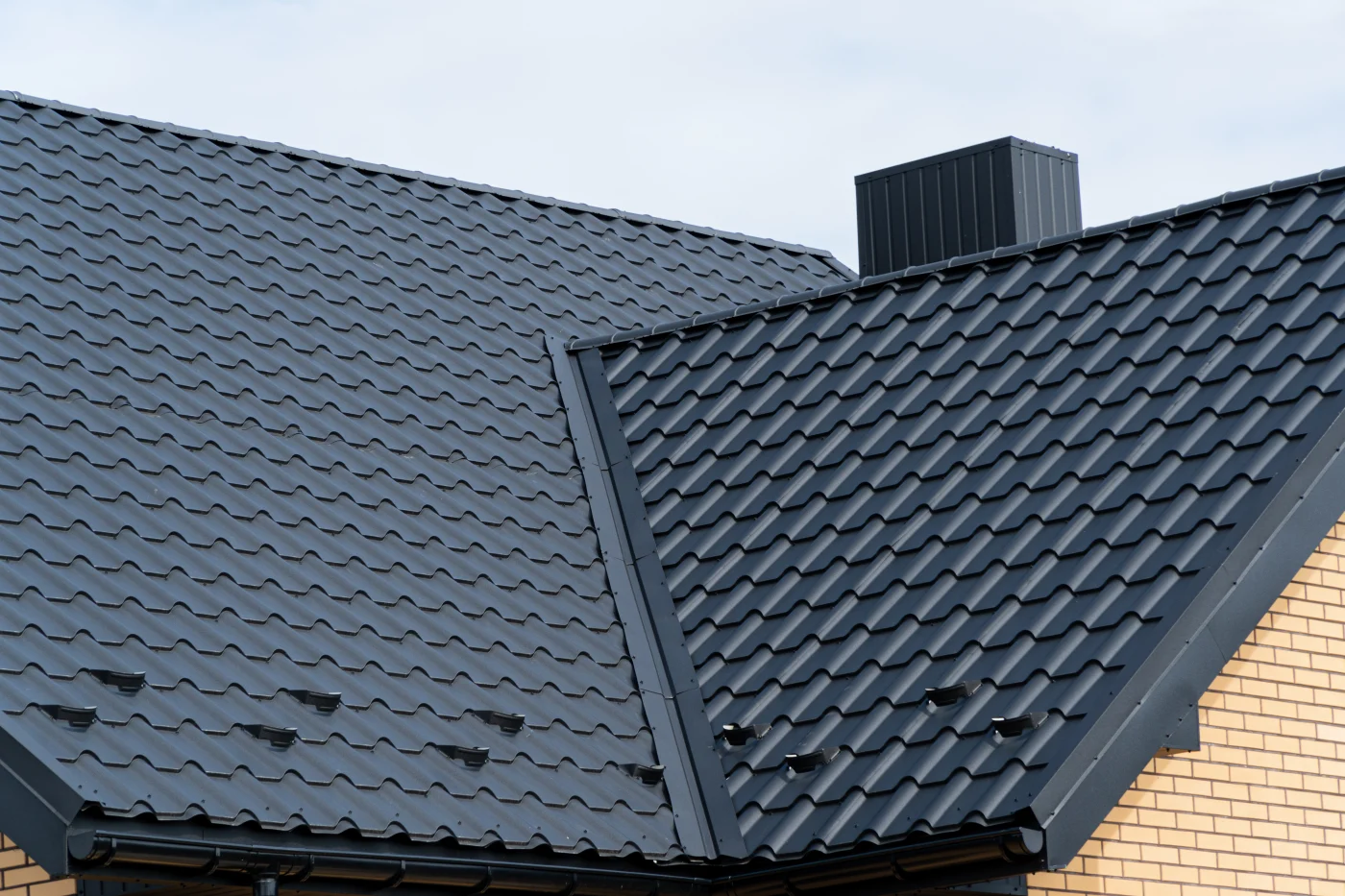 The Roof Of The House Is Covered With New Black Metal Tiles. Modern Roof Made Of Metal. Modern Construction The Roof Of The House Is Covered With New Black Metal Tiles. Modern Roof Made Of Metal. Modern Construction