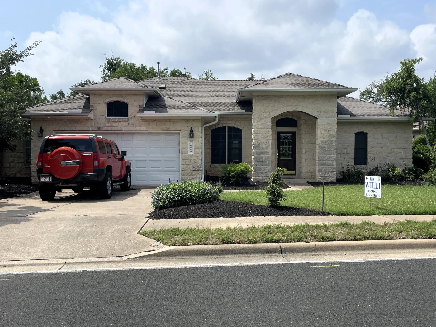 A white brick house in Bastrop County with a new asphalt shingle roof.