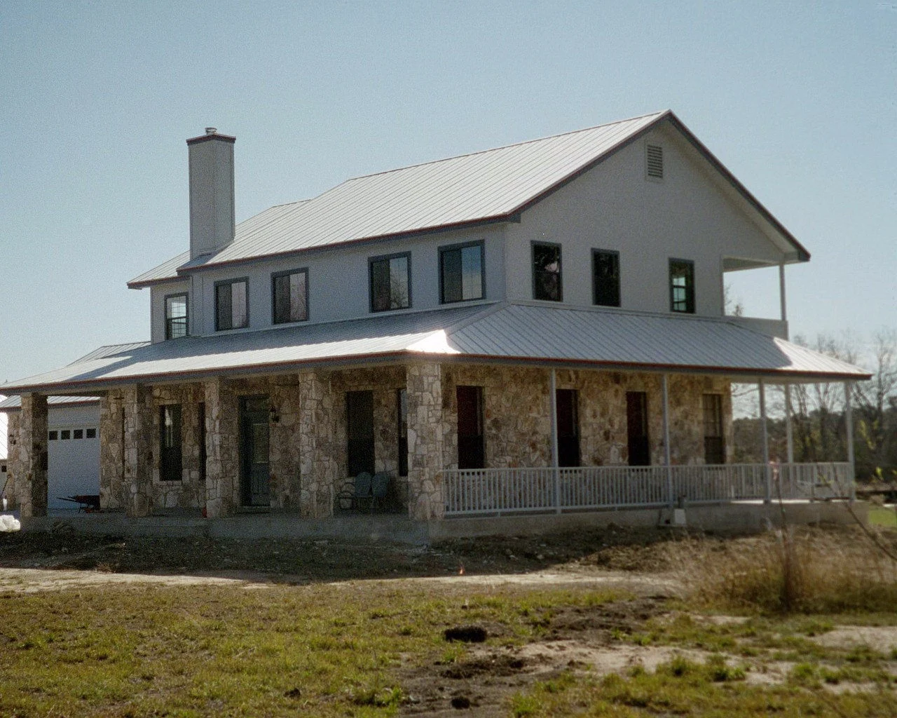 A two-story farmhouse with a metal roof in Hays County.