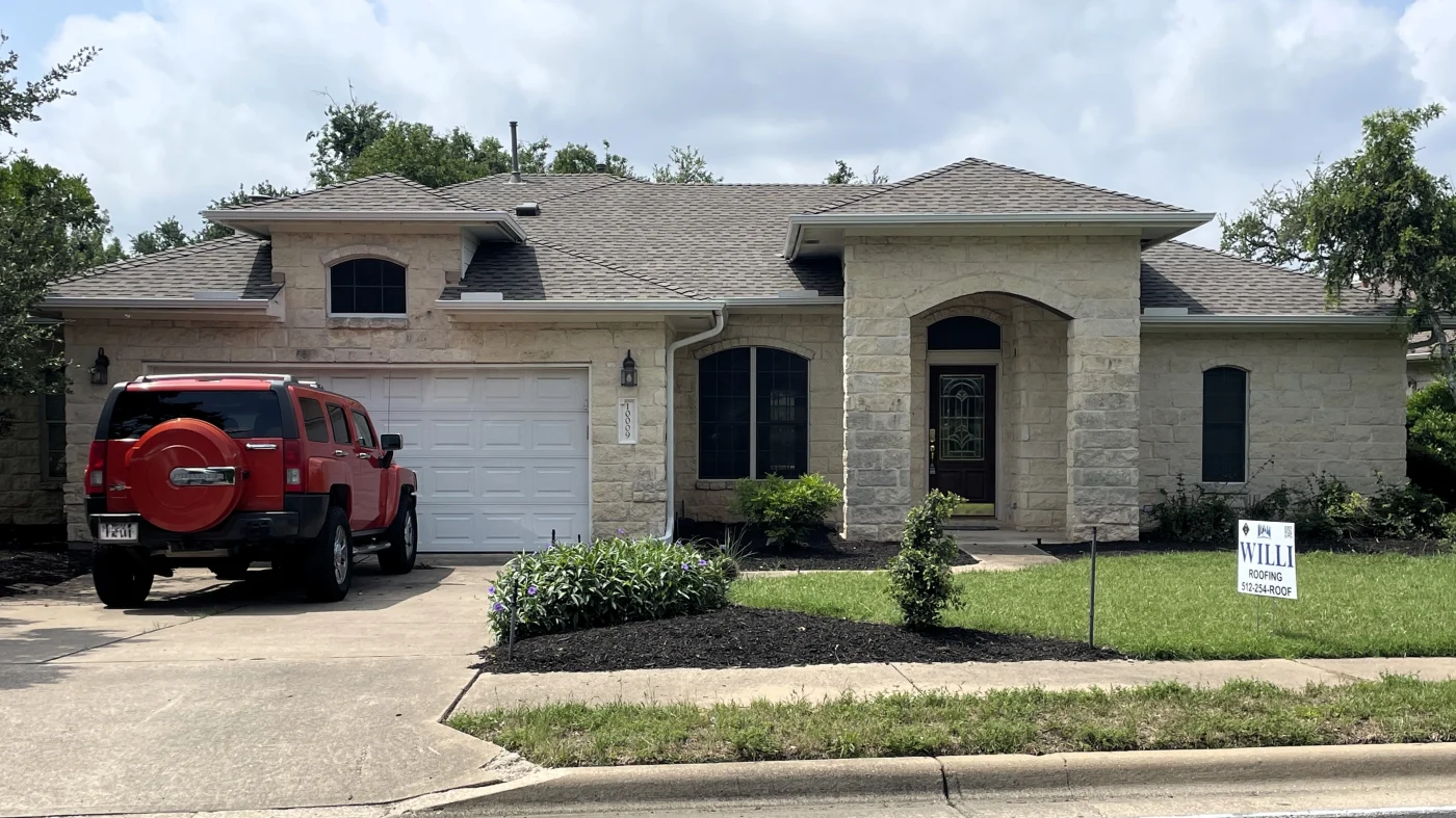 A stone house in Williamson County with a new asphalt shingle roof installed by Willi Roofing.