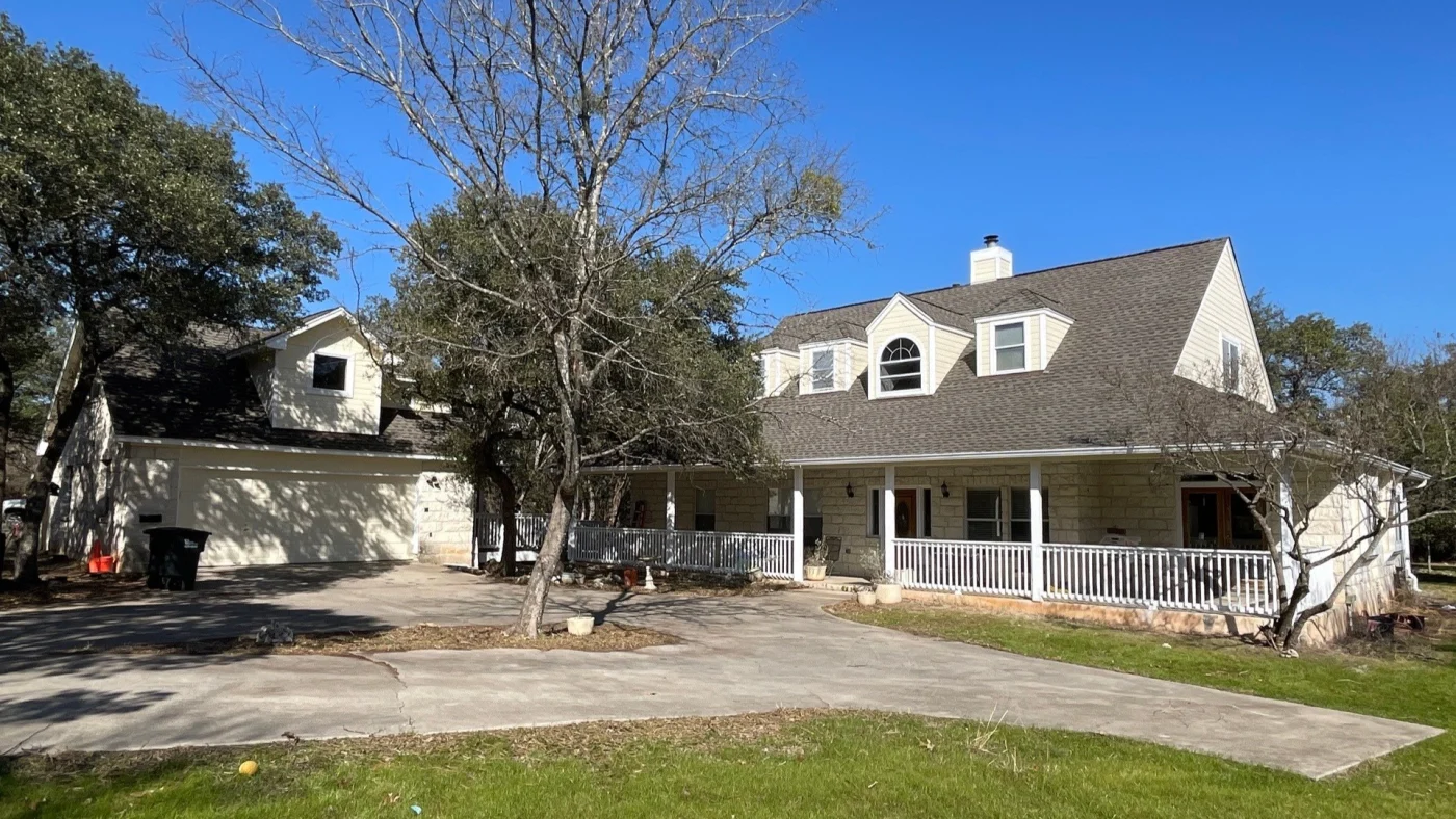 A sprawling white house in Pflugerville, TX with a new gray asphalt shingle roof.