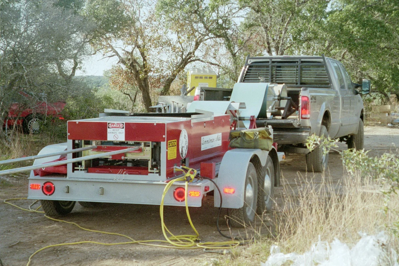 A truck from Willi Roofing hauling a metal panel machine.