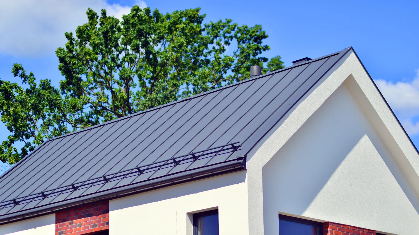 A close-up view of a black metal roof on a white building.