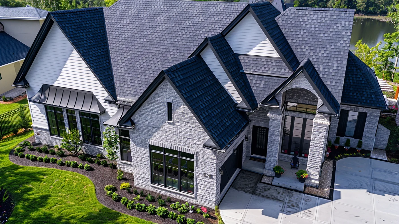 An asphalt shingle roof on a blue house with several windows.