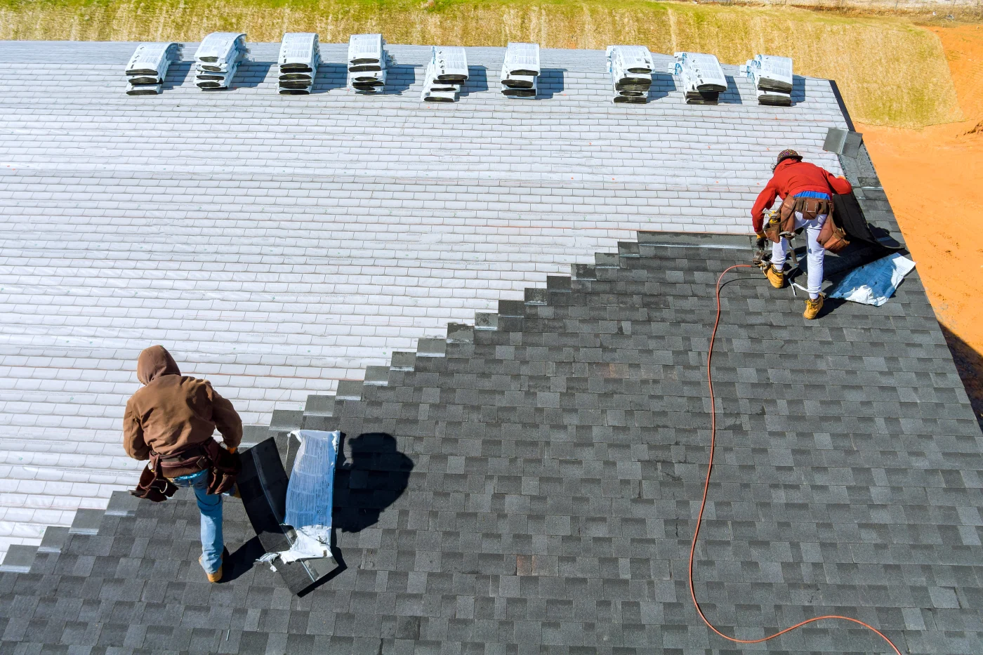 Roofers installing a new asphalt shingle roof on a house.