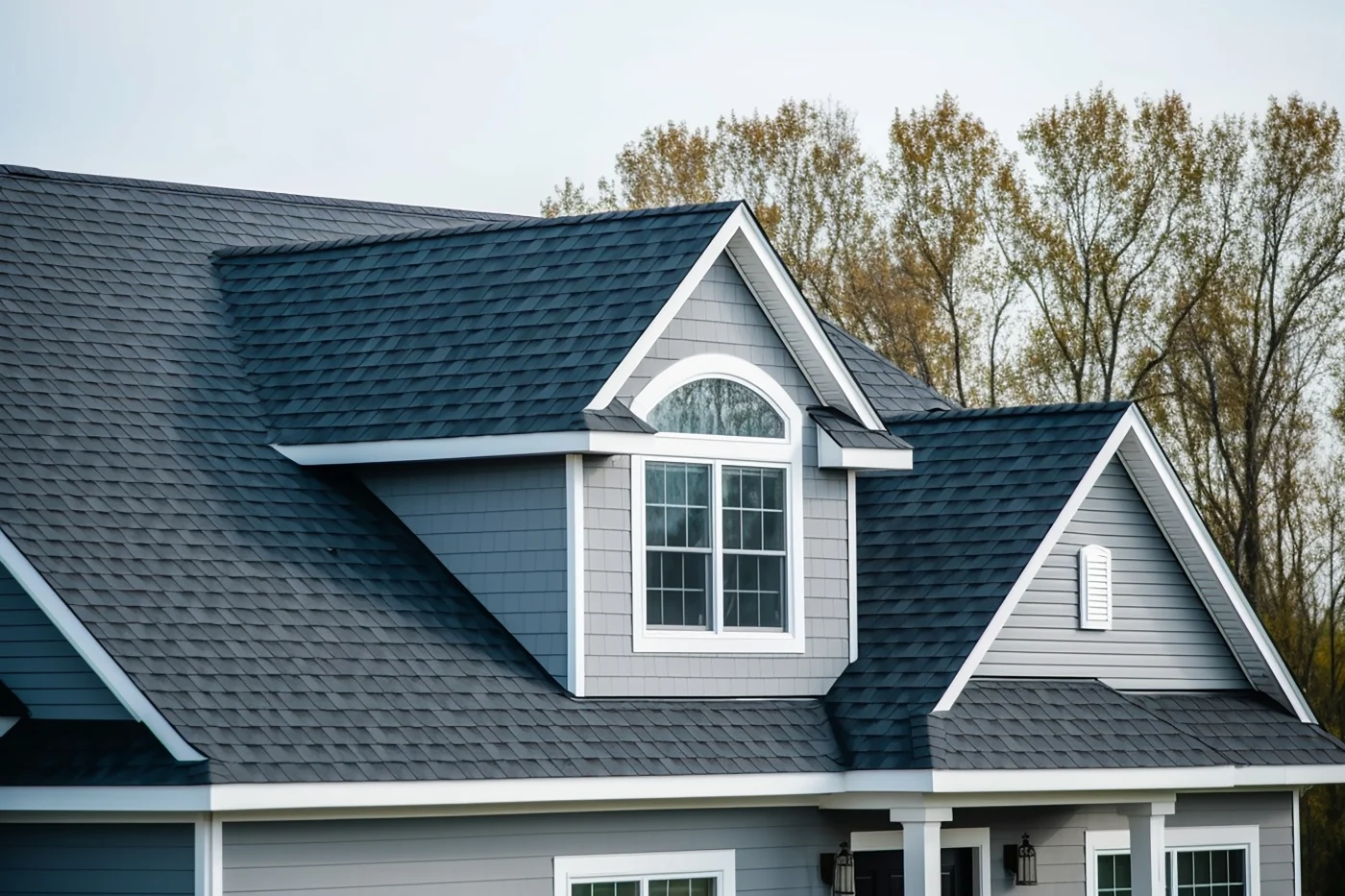A close-up view of a new asphalt shingle roof on a two-story house.