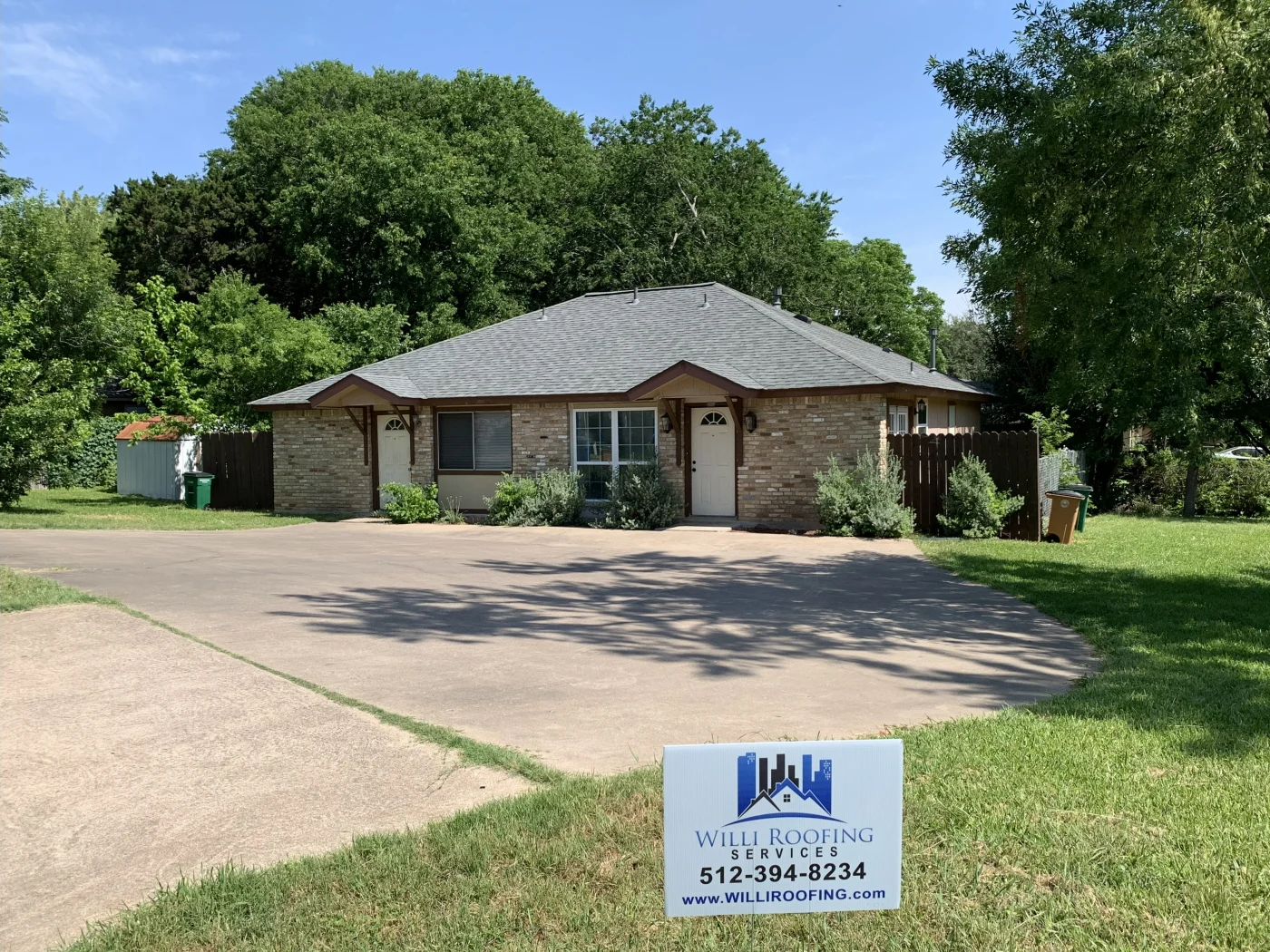 Single-story brick home with a new dark gray asphalt shingle roof and twin front entrances.