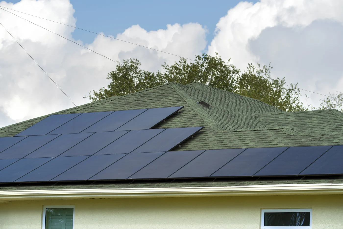 Solar panels installed on a white metal roofing system atop a brick residential home.