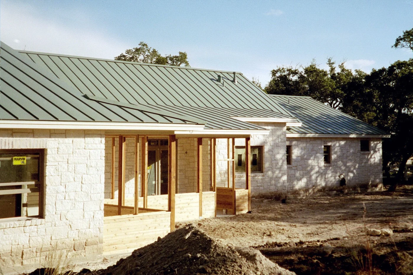 Single-story stone home with a standing seam metal roof and covered porch.