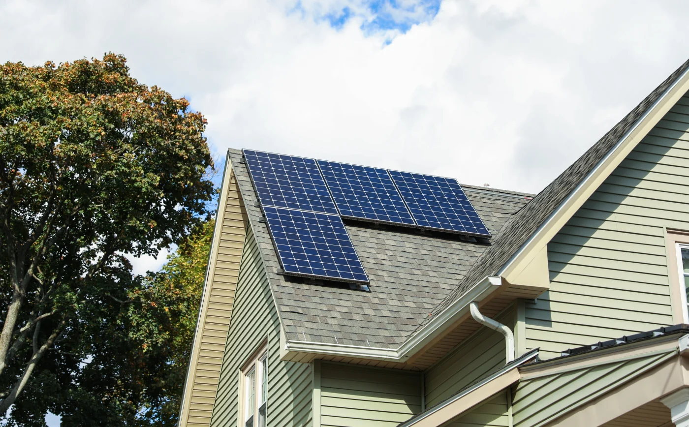 A solar panel array installed on a terracotta tile residential roof, featuring clean panel alignment and stone chimneys.