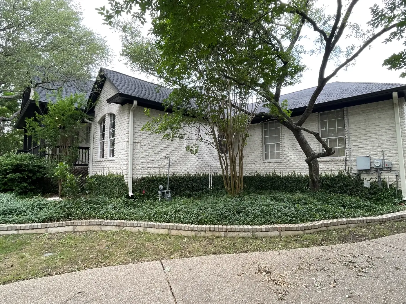 A large home with custom windows and a shingle roof.