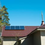 Small solar panel array mounted on a brown metal roof of a residential home