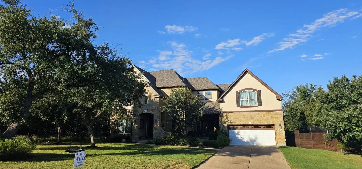A large brick home with an open garage and a car parked in the driveway.