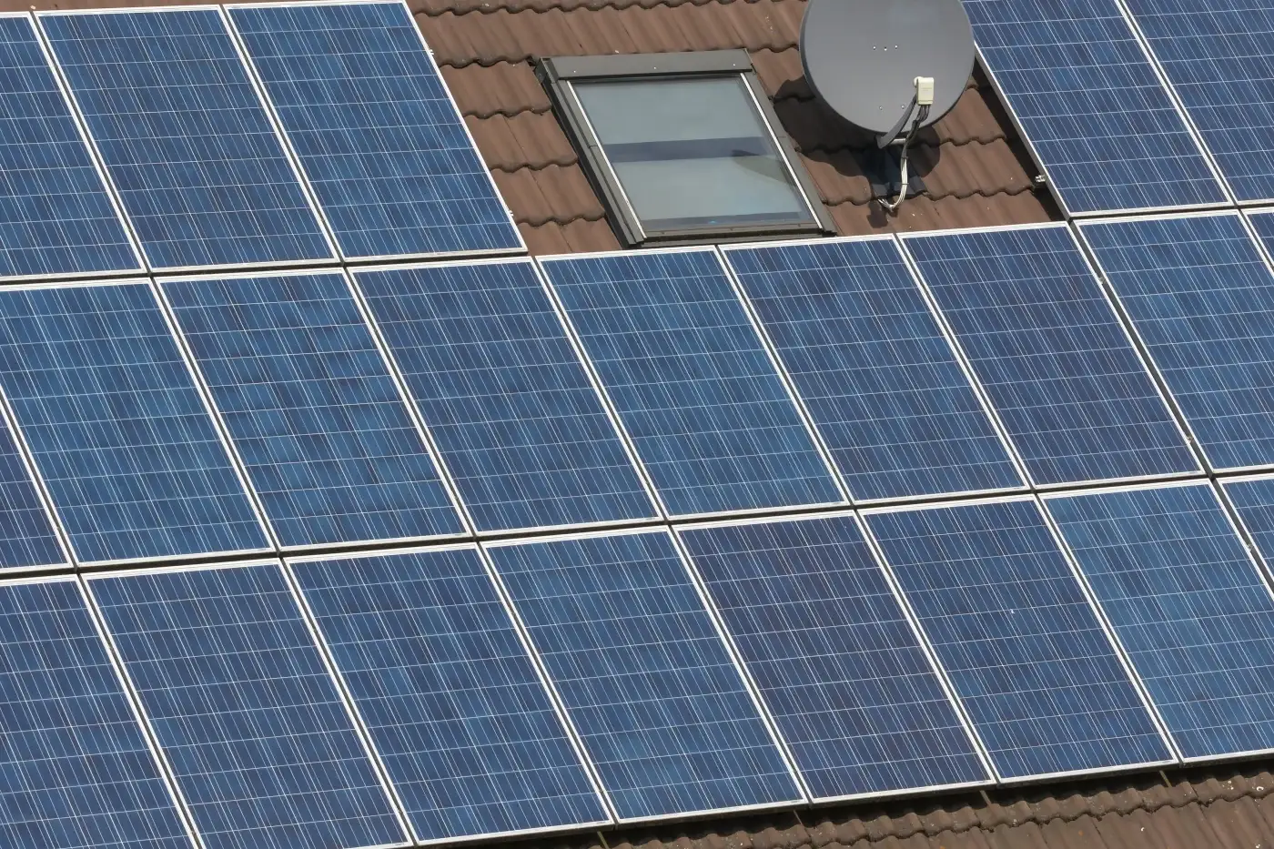 An aerial view of a roof with metal shingles and solar panels.