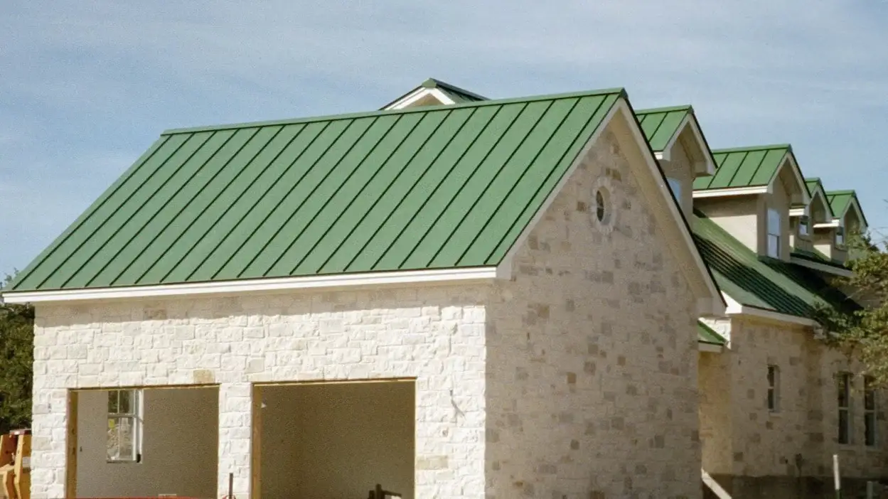 A white stone house with a green metal roof in Central Texas.