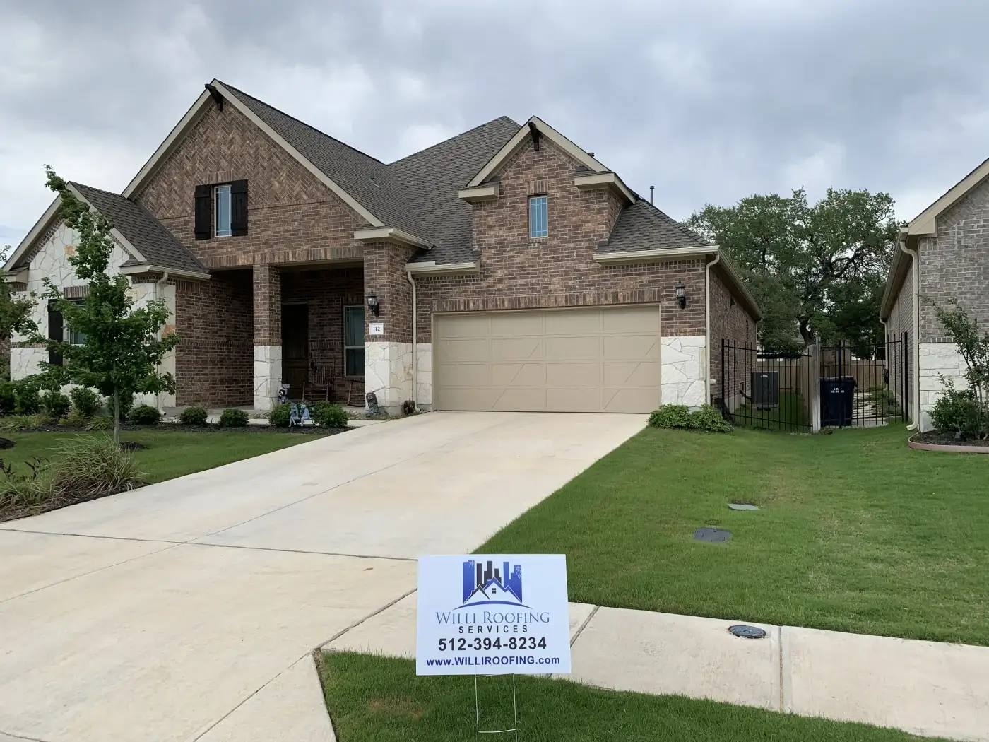 A white brick home with a gray shingle roof and a ladder leaning against the front.