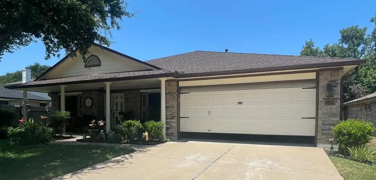 A brick home with large pillars on the front porch, a new shingle roof, and an attached garage.